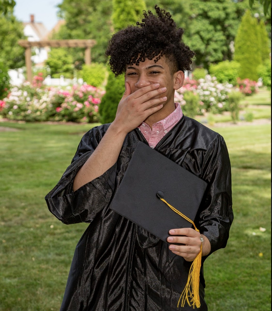 Happy graduate holding graduation cap and smiling